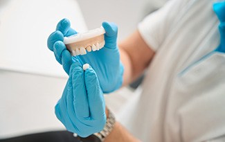 A dentist holding a mouth mold and a dental crown in preparation for placement 