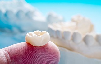 A dental crown in Lincoln resting on a fingertip 