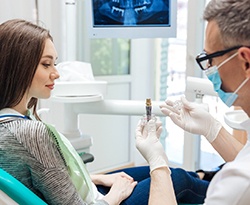 A dentist showing his patient a dental implant