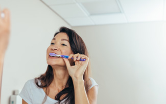 Woman brushing her teeth in bathroom